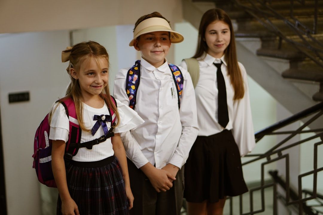 Drei Kinder in Schuluniform mit Rucksäcken, bereit für den Hotelaufenthalt.